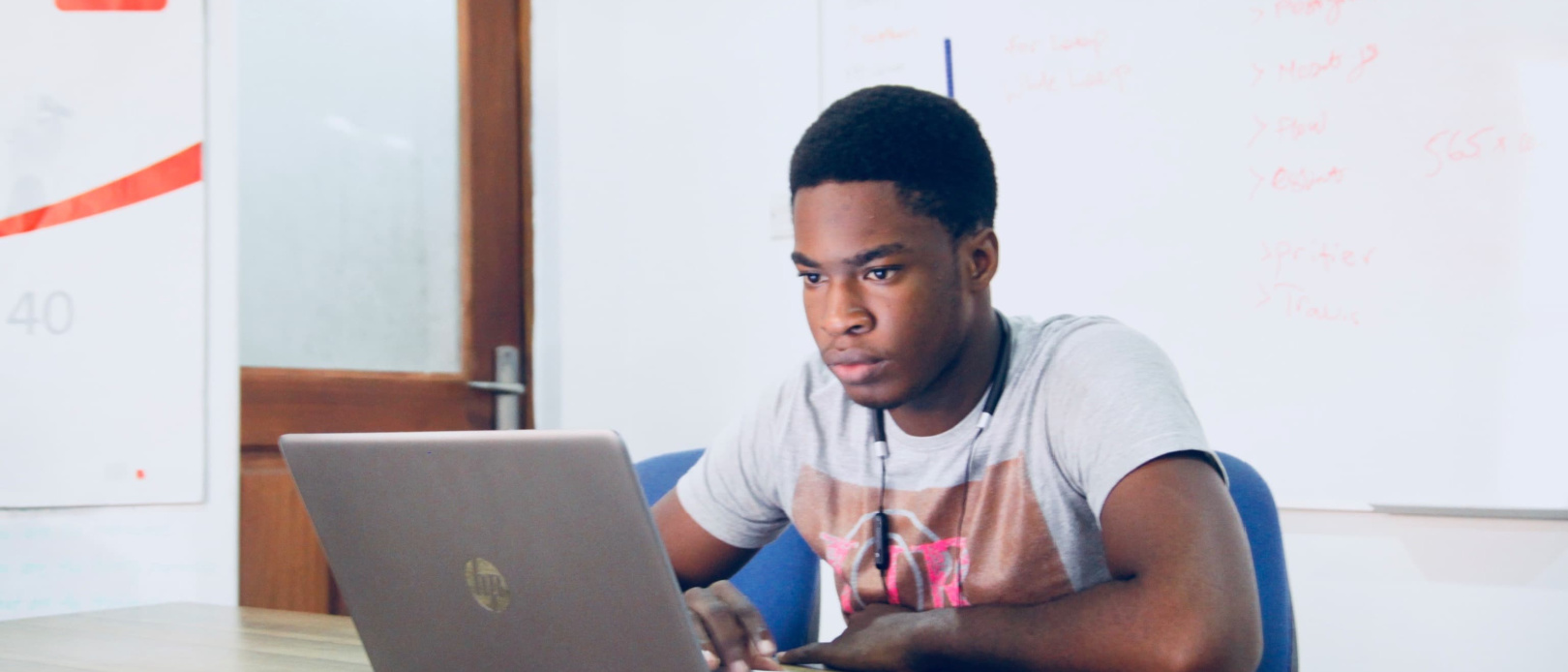 young person sitting at wide desk looking at laptop, scrolling